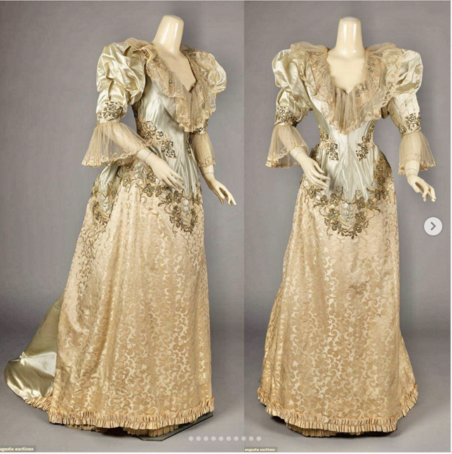 A floor length off white ball gown. The sleeves are puffy, 3/4 in length. The chest has lace ruffles and dips narrowly towards the waist.