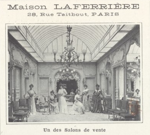 Shows the inside of abuilding. Has a chandelier in the center with three woman standing underneath. On the right and left sides see pieces of furniture.