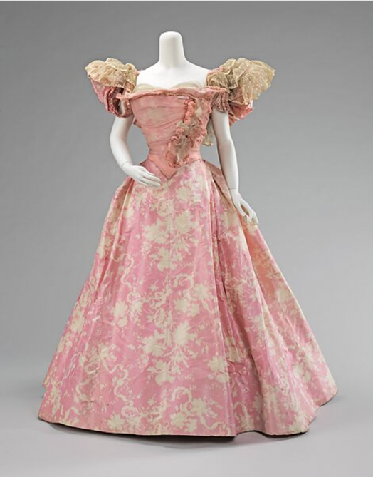A pink ball gown with cuff sleeves and ruffled tulle at the end. Along the torso of dress, there is ruffled detailing.