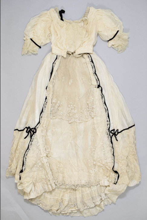 A white lace gown with black cording on the left and right sides.